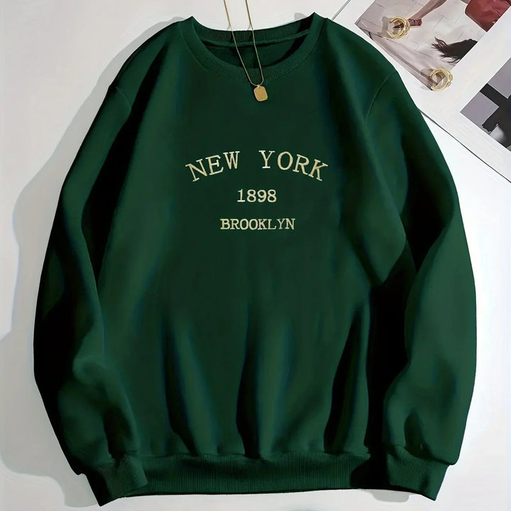 Dark green sweatshirt with New York Brooklyn 1898 text embroidery and a gold pendant necklace