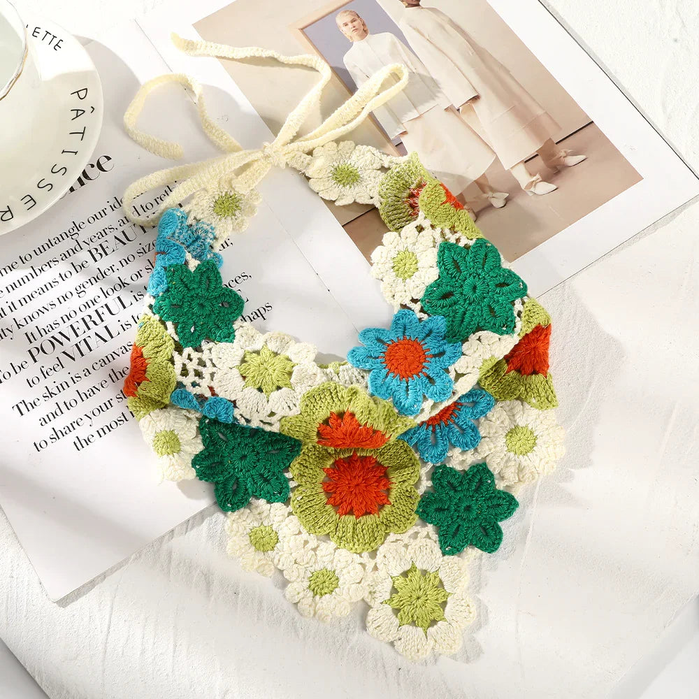 Colorful handmade crochet floral collar with green, blue, orange, and cream flowers on magazine pages