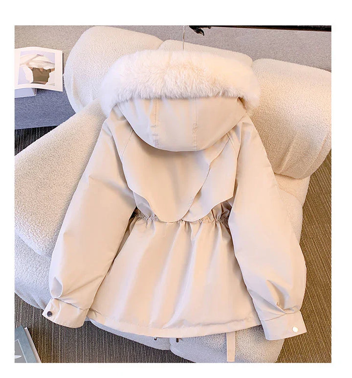 Beige winter jacket with faux fur hood trim laid on white textured armchair