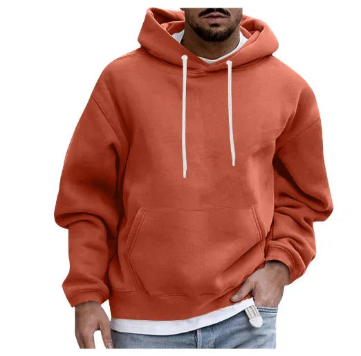 Man wearing rust orange hoodie with white drawstrings and front pocket, styled with light blue jeans