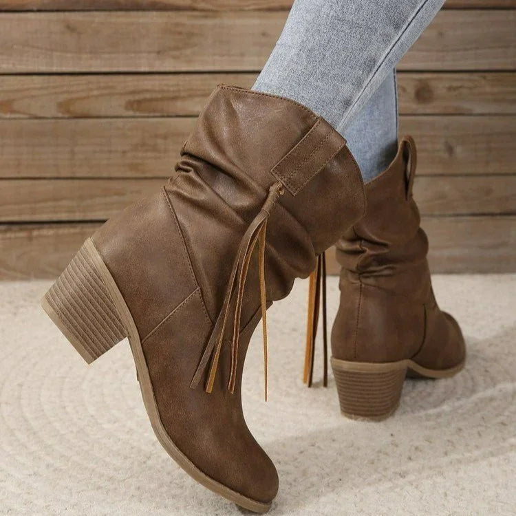 brown slouchy ankle boots with tassel detail and stacked heels worn with grey jeans