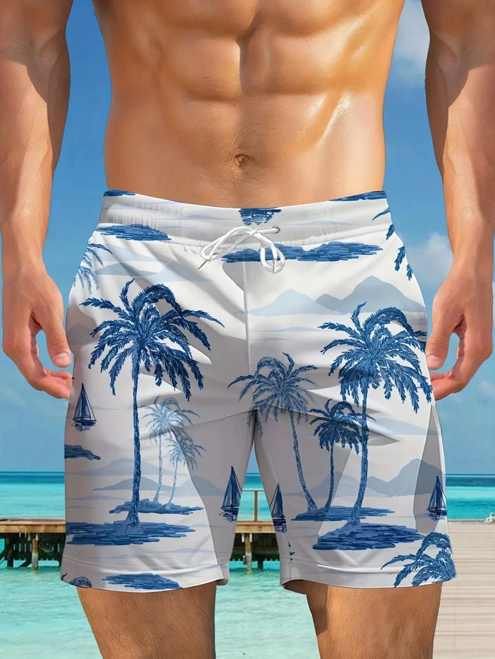 Close-up of man's torso wearing white swim shorts with blue palm tree and sailboat print at beach pier