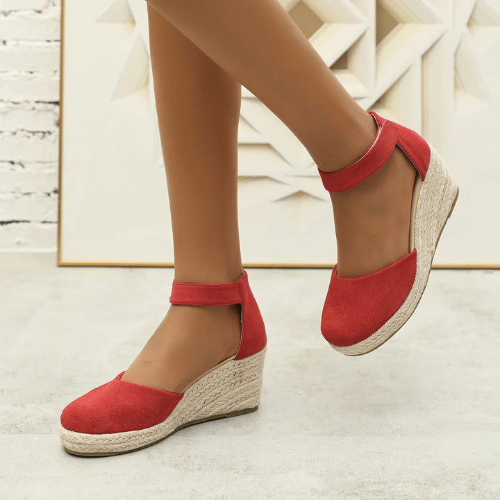 Red suede ankle strap wedge espadrilles on model feet on light background