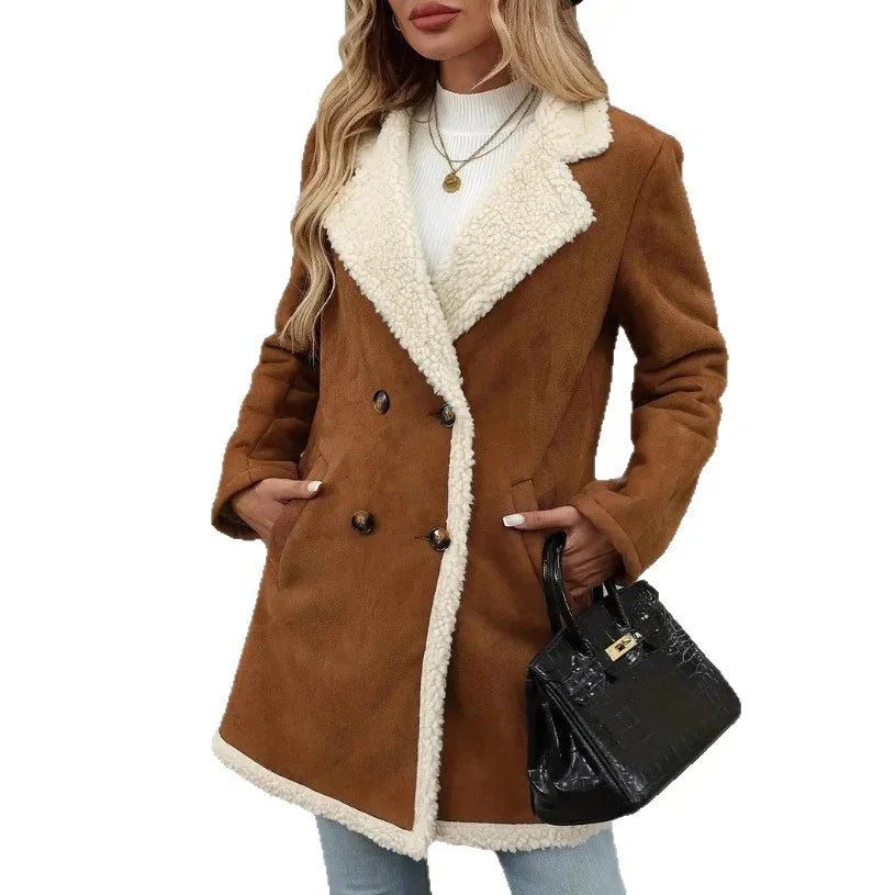 Woman wearing brown shearling coat with white faux fur lining, white sweater, blue jeans, holding black handbag