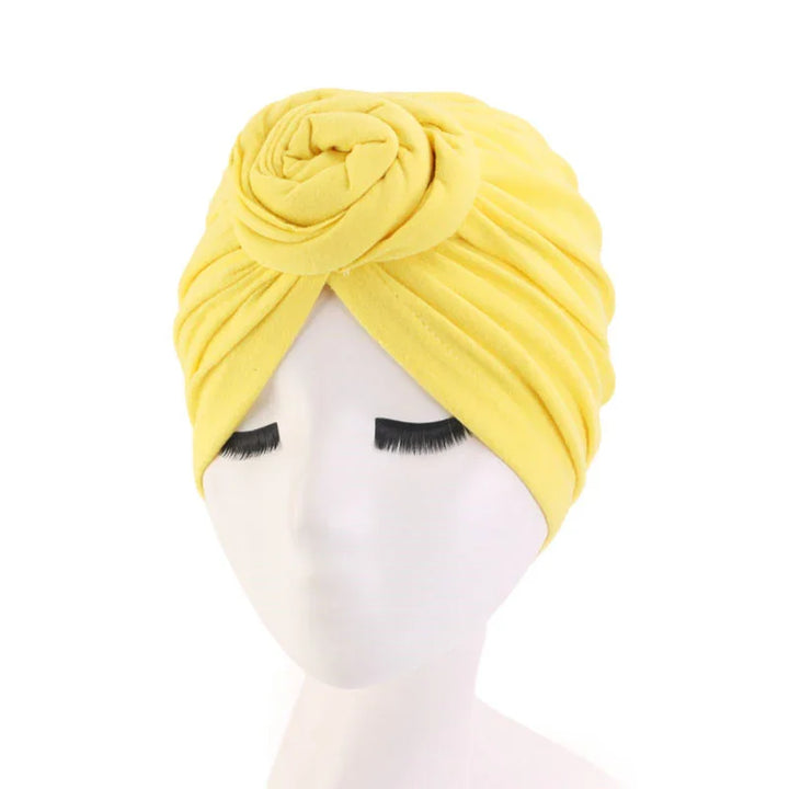 Soft yellow turban headwrap with rose detail on white mannequin head