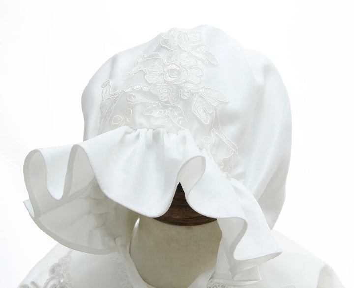White satin bonnet with floral embroidery and ruffled edge on mannequin