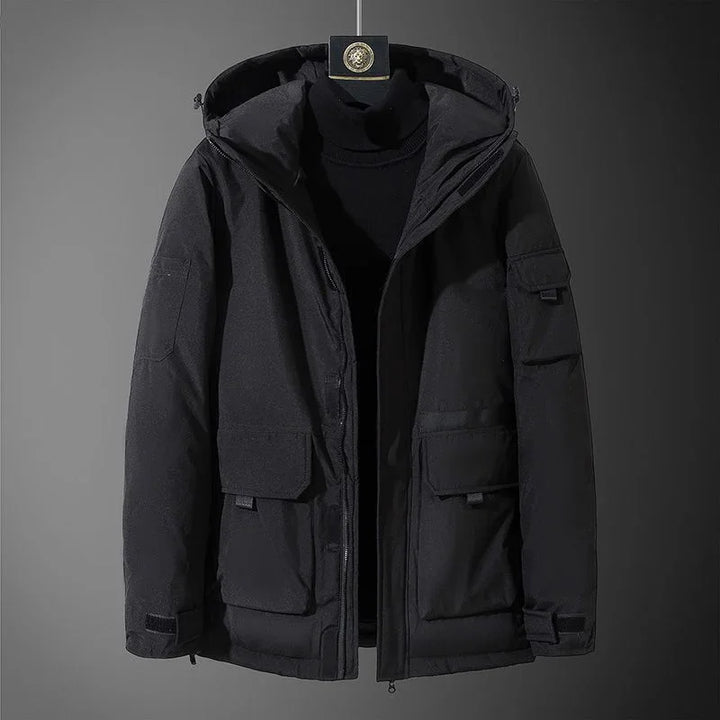 Black hooded winter jacket with front flap pockets and zipper on display against dark background