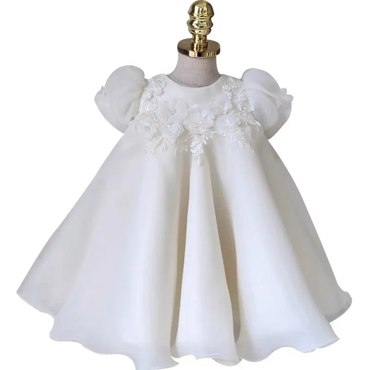 White baby dress with puffed sleeves and floral lace embroidery on bodice displayed on mannequin