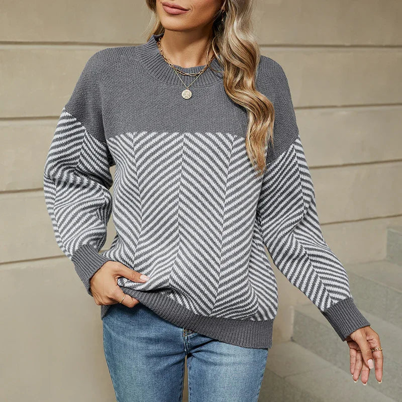 Woman wearing gray and white chevron knit sweater with round neckline and blue jeans