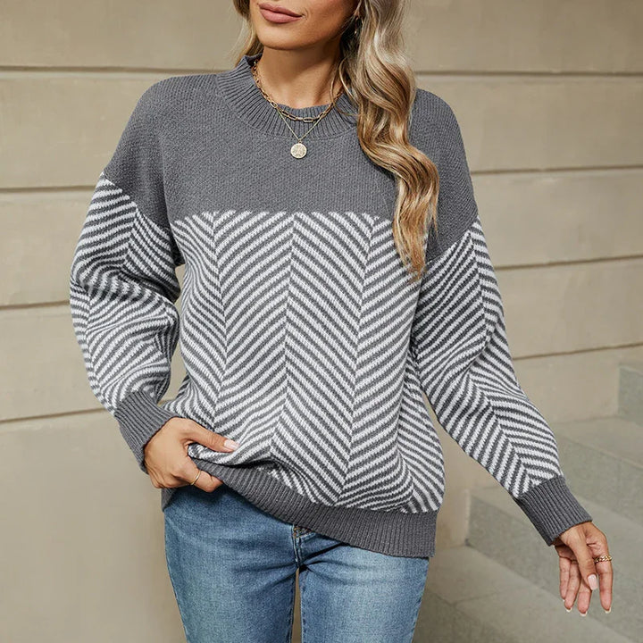 Woman wearing gray and white chevron patterned knit sweater with round neck and long sleeves