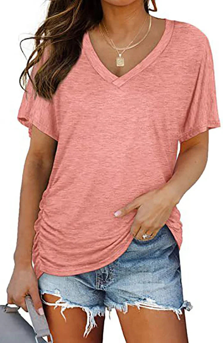 Woman wearing pink V-neck short sleeve shirt and ripped denim shorts holding a bag