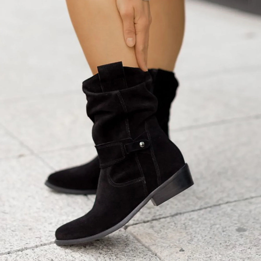 Black suede mid-calf boots with low block heel worn on sidewalk