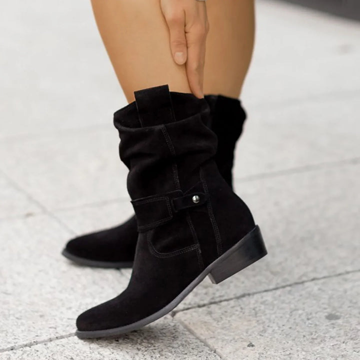 Black suede mid-calf boots with low block heel worn on sidewalk