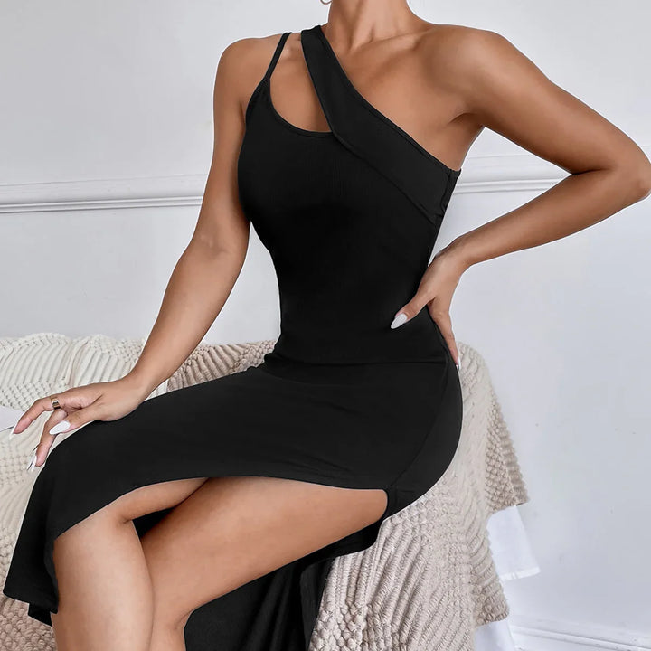 Woman wearing a black one-shoulder midi dress with a side slit, seated indoors