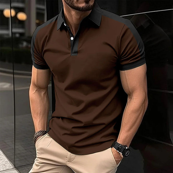 Muscular man wearing brown and black short-sleeve polo shirt with beige pants, standing with hands in pockets