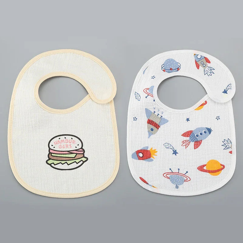 Two baby bibs on gray background, one with hamburger print and one with colorful space rocket design