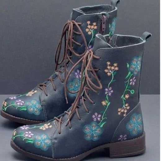 Blue lace-up boots with colorful floral embroidery and side zipper against gray background