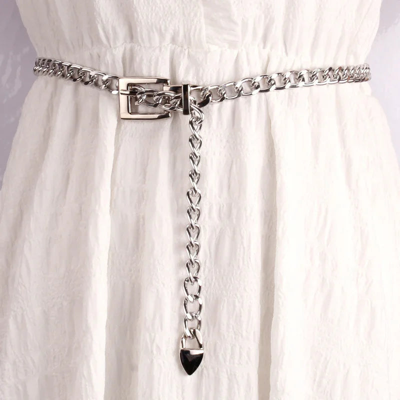 Silver chain belt with buckle detail worn on textured white fabric dress