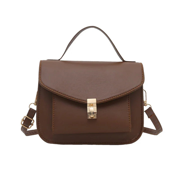 Brown leather handbag with top handle, gold clasp, and adjustable shoulder strap on white background