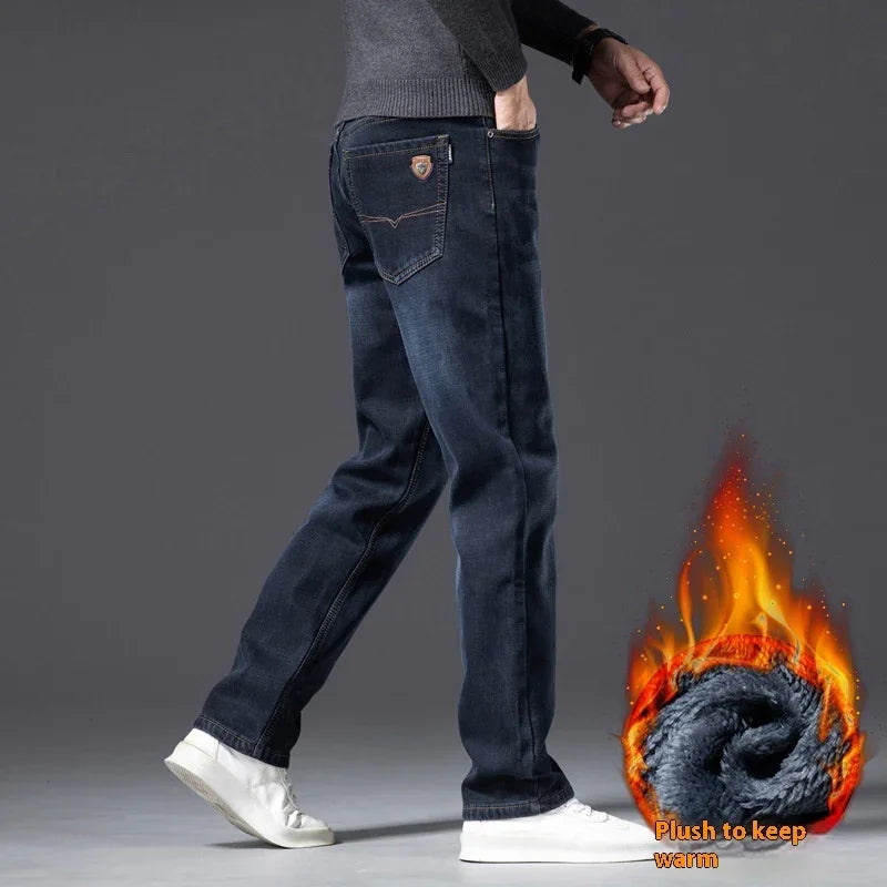 Man wearing dark blue thermal jeans paired with white sneakers against gray background