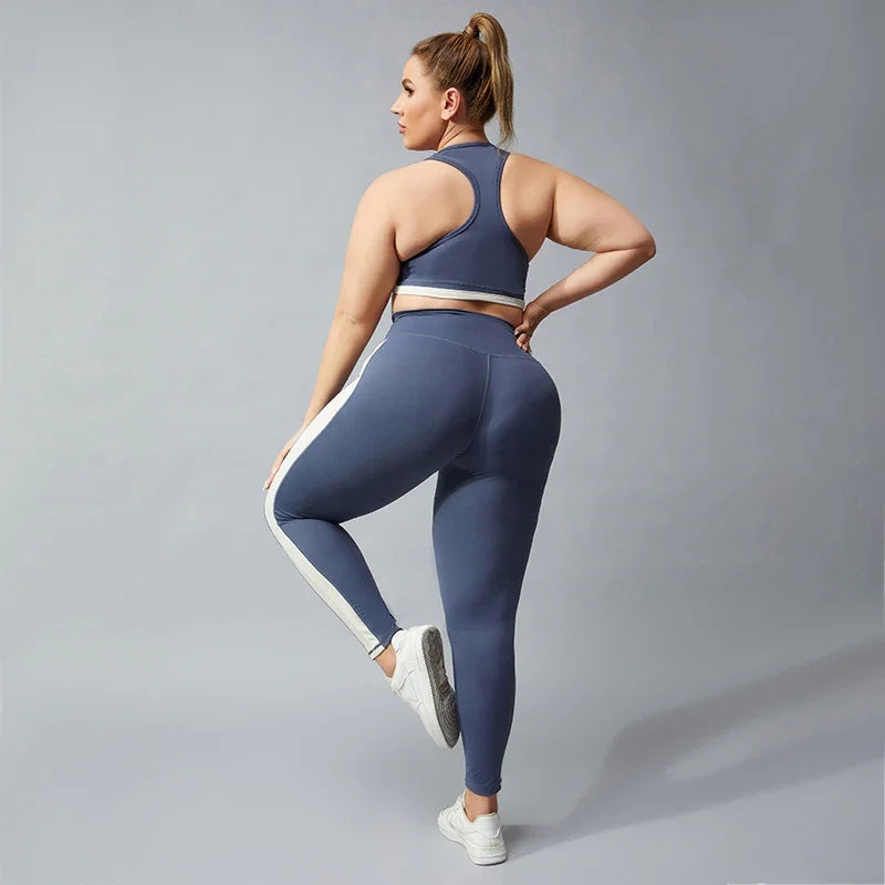 Plus size woman in blue and white striped leggings and matching sports bra posing against gray background