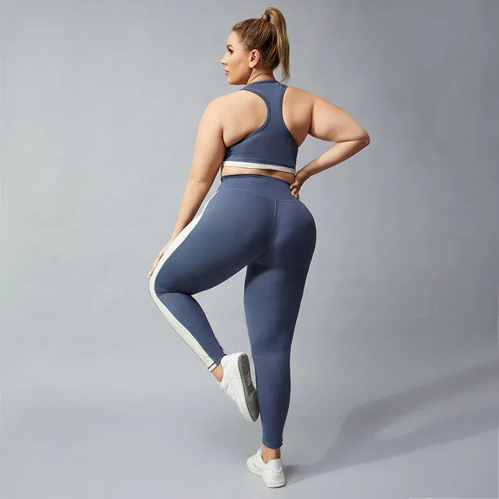 Plus size woman in blue and white striped leggings and matching sports bra posing against gray background