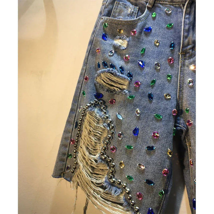 Distressed blue jeans decorated with multicolored rhinestones and silver bead trim