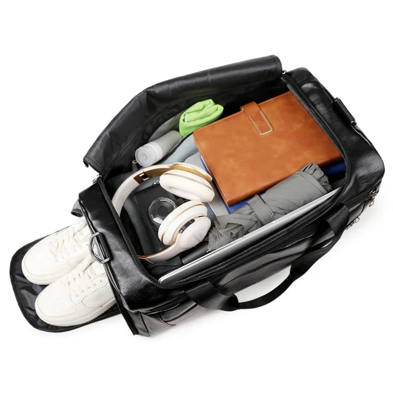 Open black leather travel bag packed with white sneakers, headphones, umbrella, notebook, and clothes