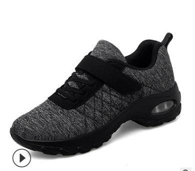 Grey and black athletic sneaker with knit upper, air cushion sole, black strap, and pull tab