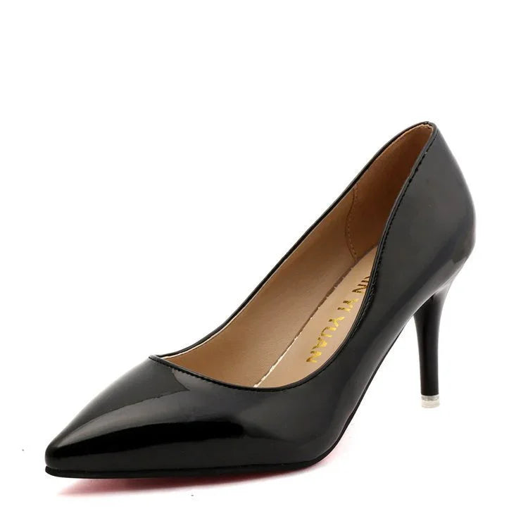 Black patent leather pointed toe high heel pump with beige inner lining on white background