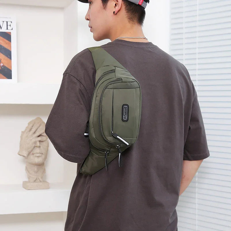 Man wearing an olive green crossbody sling bag with multiple zippered compartments