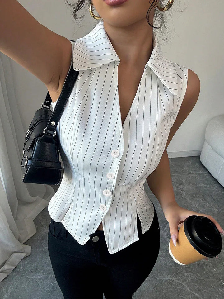 Woman wearing sleeveless white pinstripe button-up top with black pants, holding coffee cup and black purse