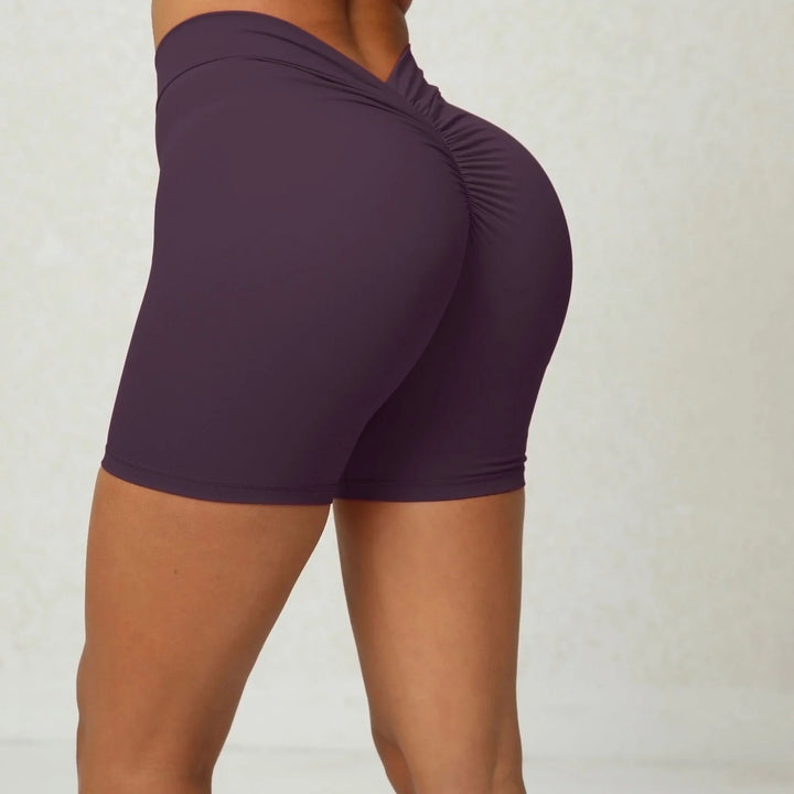 Close-up of woman wearing dark purple scrunch workout shorts enhancing curve fit