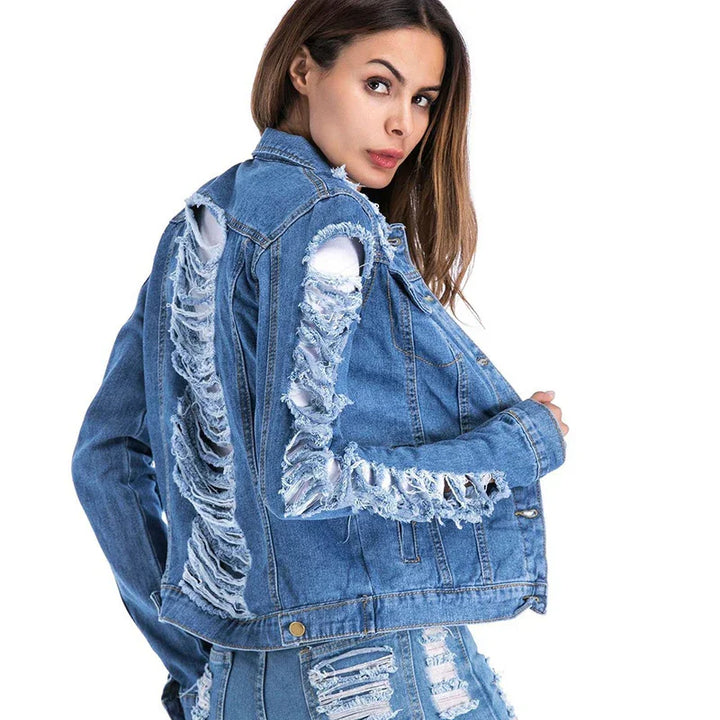 Woman wearing fashion distressed blue denim jacket and matching ripped jeans on white background