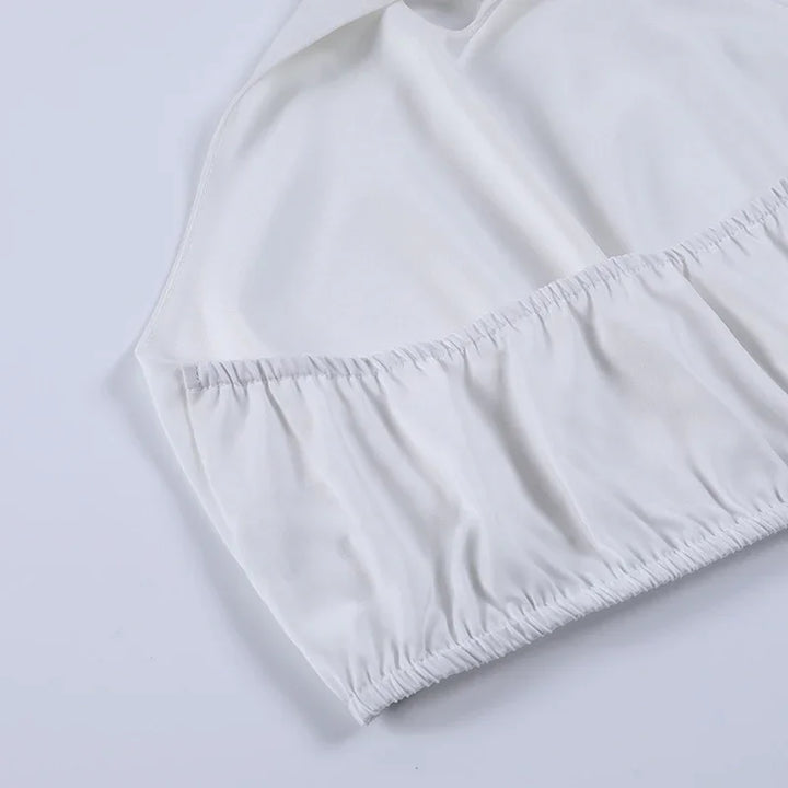 White fitted sheet with elastic edges, smooth fabric close-up on light background