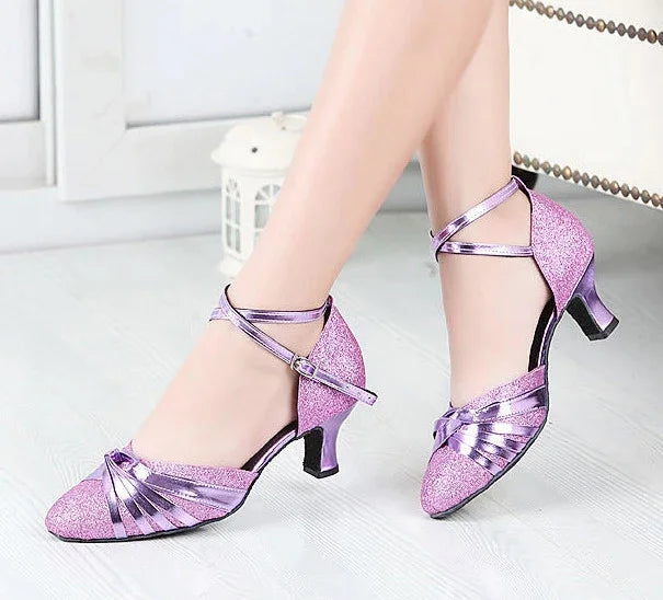 sparkling purple dance shoes with ankle straps on light wooden floor