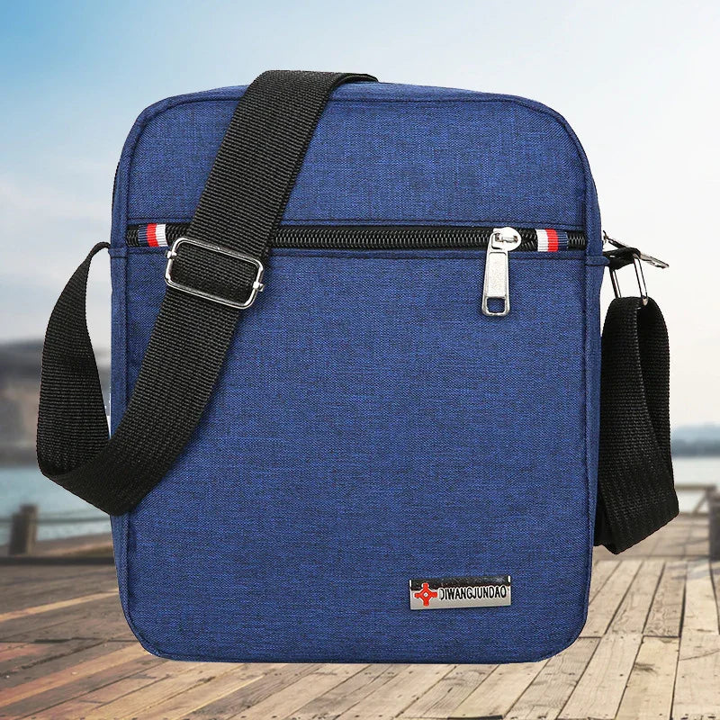 Blue crossbody bag with black adjustable strap on wooden pier background