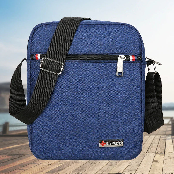 Blue crossbody bag with black adjustable strap on wooden pier background