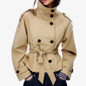 Woman wearing beige short trench coat with double-breasted buttons and waist tie belt