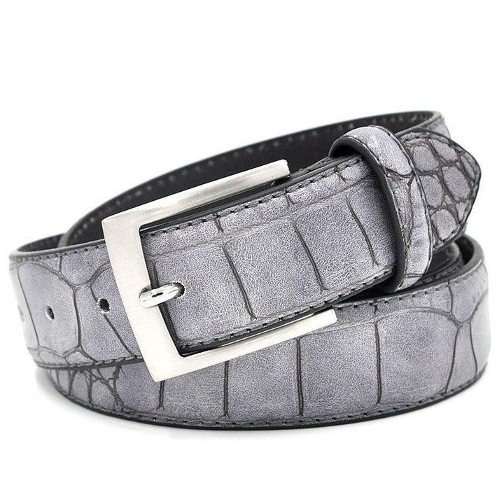 Gray leather belt with crocodile texture and silver buckle rolled up on white background