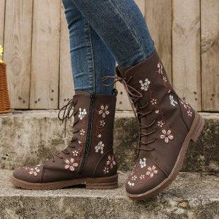 Brown lace-up boots with floral embroidery worn with blue jeans on stone steps