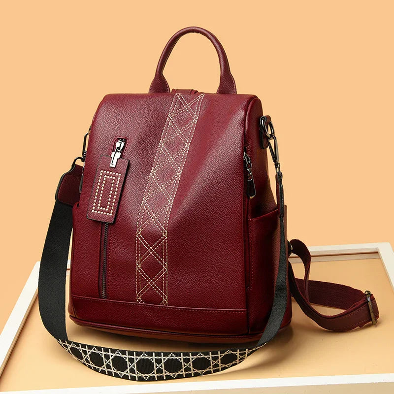 Stylish maroon leather backpack with beige stitched pattern and adjustable black shoulder strap