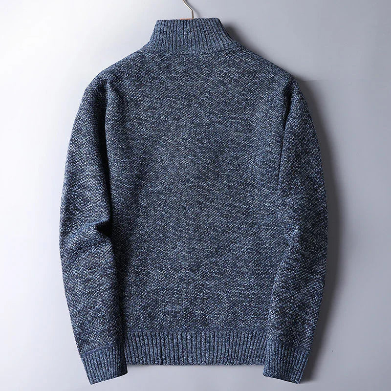 Back view of a blue textured knit turtleneck sweater hanging on a hook