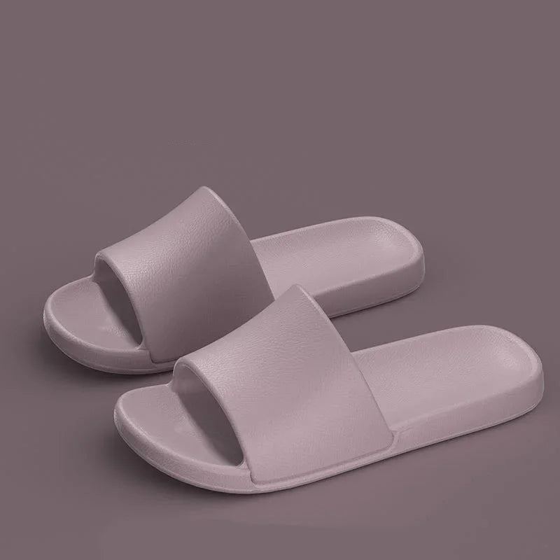 Minimalist mauve slide sandals with open toes on a matching mauve background