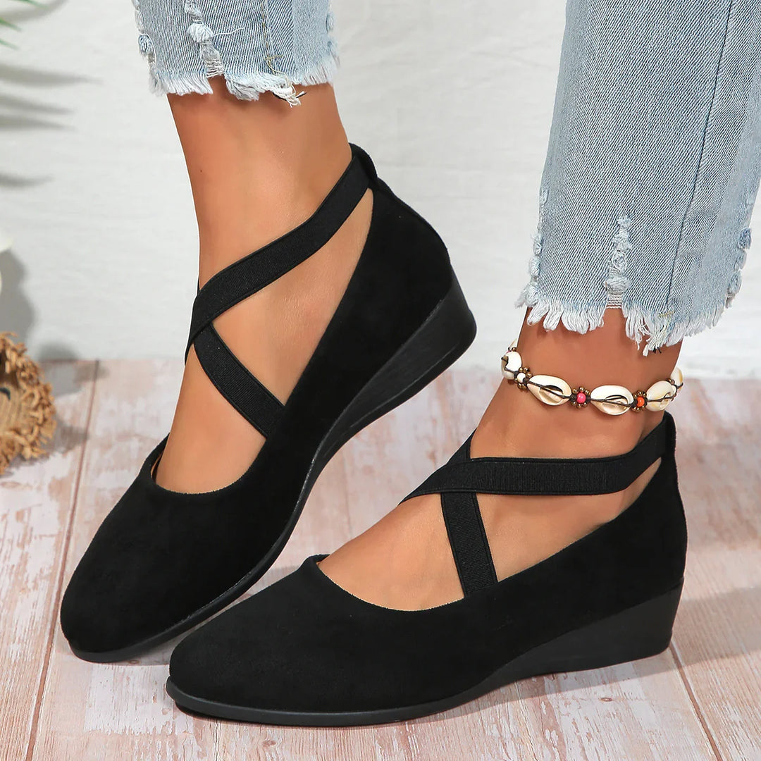 Black suede wedge shoes with crisscross straps worn with distressed light blue jeans and shell anklet
