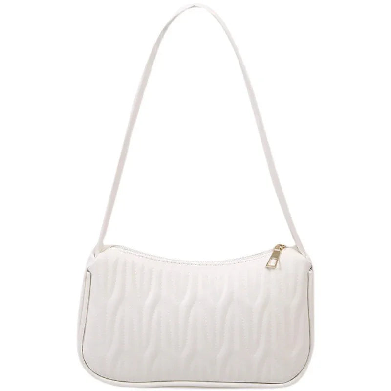 White shoulder handbag with quilted wave pattern and gold zipper on white background