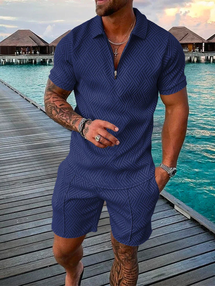 Man wearing blue textured short-sleeve polo and matching shorts on wooden pier over turquoise water