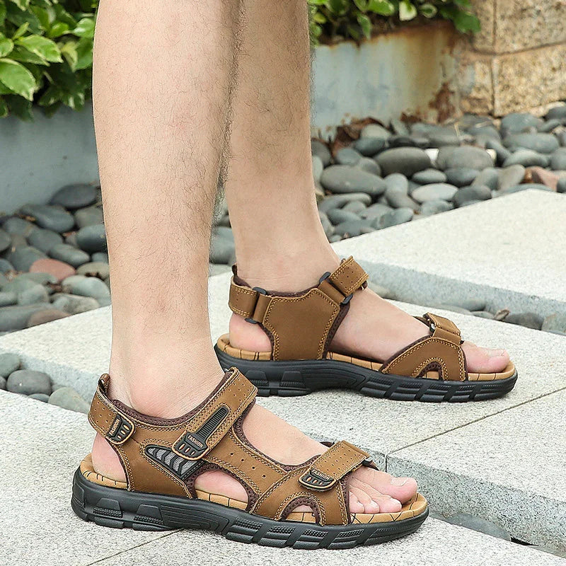 Men's brown leather sports sandals with black soles worn outdoors on stone steps