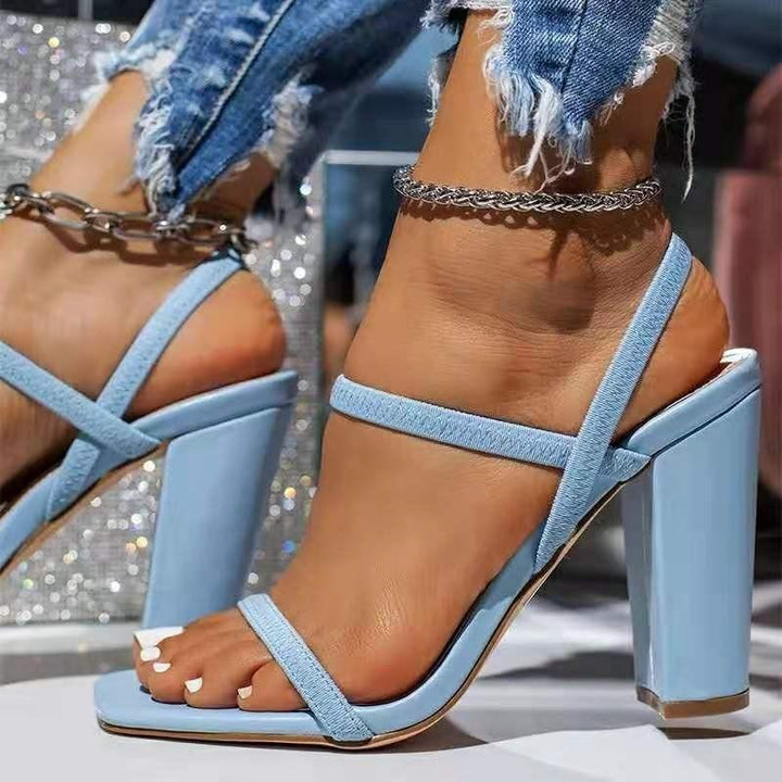 Close-up of feet wearing light blue high-heeled sandals with distressed denim jeans and silver anklets