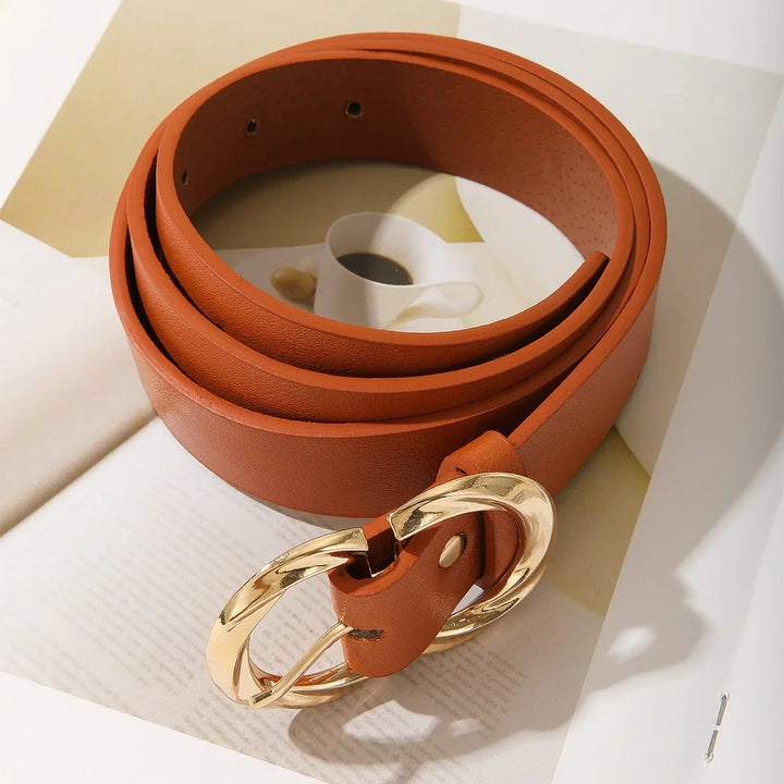 Brown leather belt with gold oval buckle on open book with coffee cup image